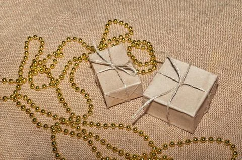 Christmas boxes in craft paper lie on the table, decorated with gold ribbons and Stock Photos