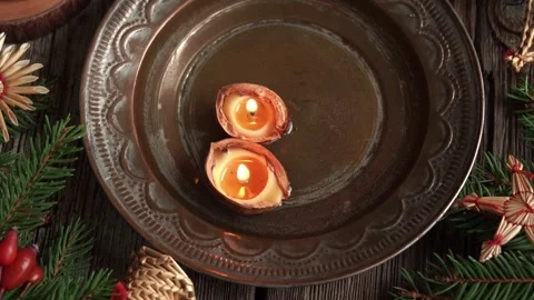 Christmas candles made of walnut shells and beeswax floating in a bowl of water Stock Footage 330492679