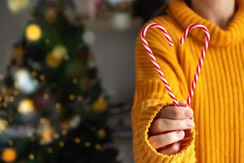 Christmas candy cane in hands in the shape of a heart on the background of a Foto stock