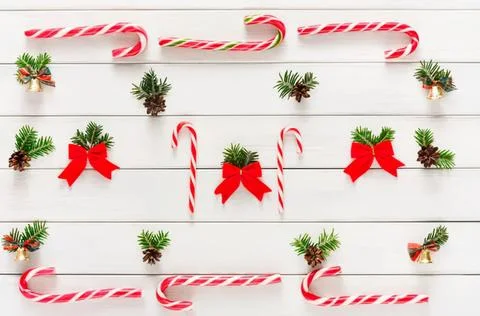 Christmas candy canes, pine branches, and red bows on white wood Stock Photos