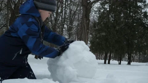 Christmas classes. a boy in a blue jacket rolls a ball of snow Stock Footage 147206039