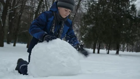 Christmas classes. a boy in a blue jacket sculpts snow in the park Stock Footage 147339866