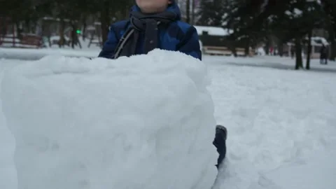 Christmas classes. a boy in a blue jacket tries to move a clod of snow Stock Footage 147401774