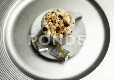 Christmas coffee with whipped cream and a small gift on ceramic saucer Stock Photos
