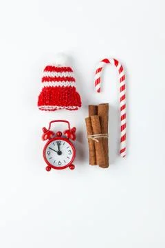 Christmas composition, cane candy, small analog clock, striped hat on white b Stock Photos