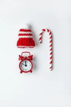 Christmas composition, cane candy, small analog clock, striped hat on white b Stock Photos