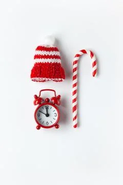 Christmas composition, cane candy, small analog clock, striped hat on white b Stock Photos