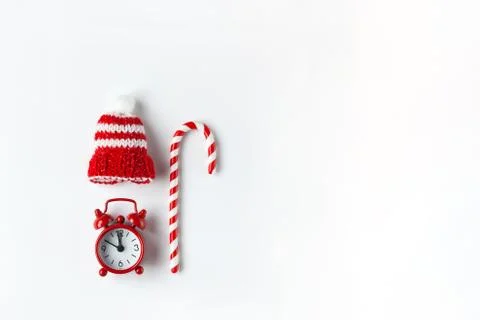 Christmas composition, cane candy, small analog clock, striped hat on white b Foto stock