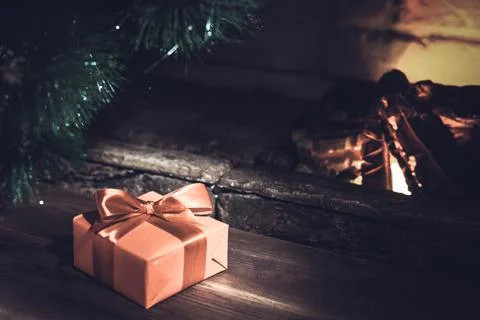 Christmas composition, gift under the tree near a burning fireplace, close-up Stock Photos