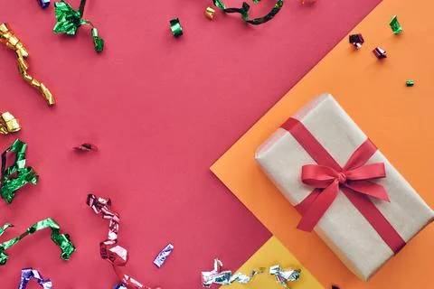 Christmas composition. Giftbox with red ribbon and confetti decorations on pa Stock Photos