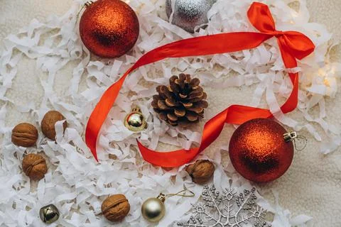 Christmas composition with pine cone, balls, nuts and red ribbon on a white snow Stock Photos