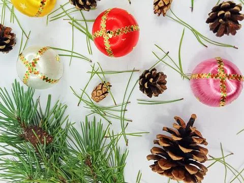 Christmas composition with pine cones and colorful ornaments on white background Stock Photos