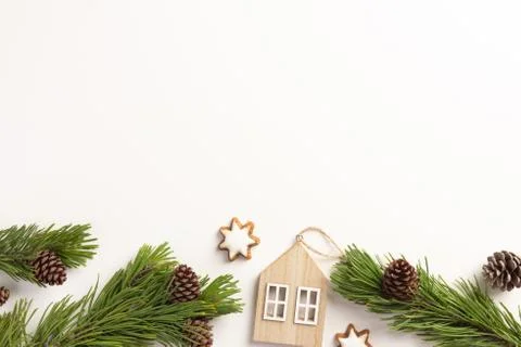 Christmas composition. Spruce branches with small wooden house, on a white ba Stock Photos