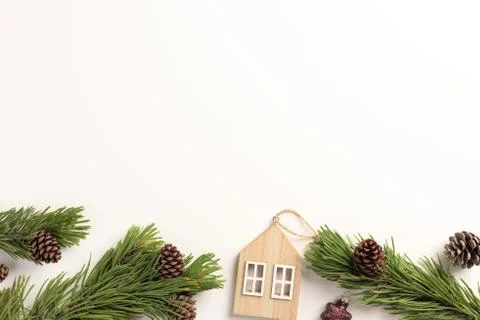 Christmas composition. Spruce branches with small wooden house, on a white ba Stock Photos