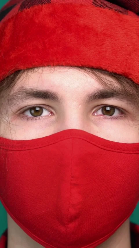 Christmas concept closeup of a guy wearing red hat and protective red mask. Stock Footage 345691736