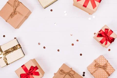 Christmas craft gift boxes create round frame on white wooden background. Stock Photos