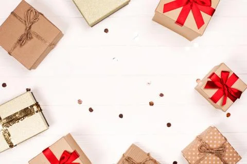 Christmas craft gift boxes create round frame on white wooden background. Stock Photos