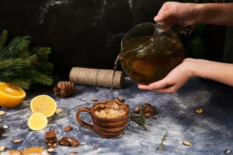 Christmas decor, ceramic cup, lemons, spruce, nuts. A man pours tea into a cup. Stock Photos