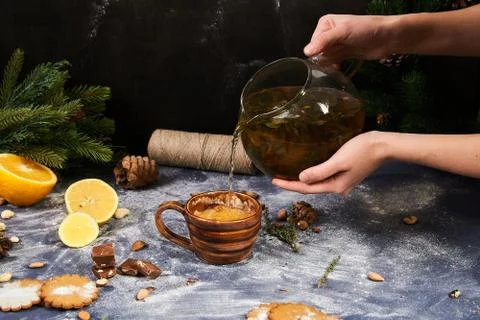 Christmas decor, ceramic cup, lemons, spruce, nuts. A man pours tea into a cup. Stock Photos