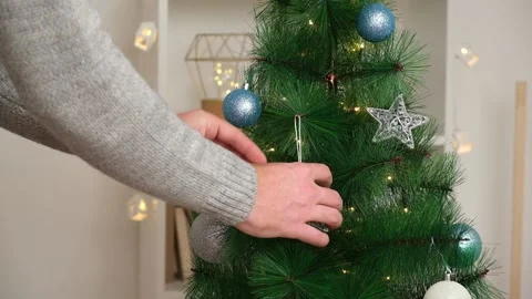 Christmas decor. A man decorates a Christmas tree with Christmas toys. Preparing Stock Footage 212789853