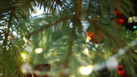 Christmas decorations hung on the tree, sparkling in the light of garlands and Stock Footage 296403018