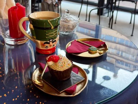 Christmas dessert setting with nutcracker mug and festive cupcake. Warm celeb Stock Photos