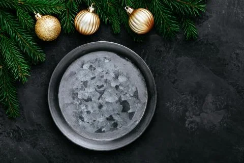 Christmas dinner background with empty plate and gold decor on dark table. Stock Photos