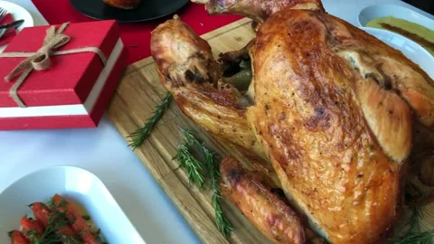 Christmas dinner table concept of whole roast turkey on wooden cutting board Stock Footage 145605566