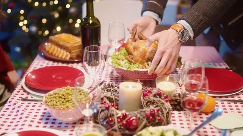 On Christmas dinner, young man placing hot turkey and sitting at table with Stock-Footage 122439858