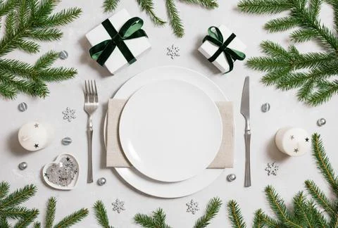 Christmas empty table setting with silver decor and fir branches on a gray ba Stock Photos