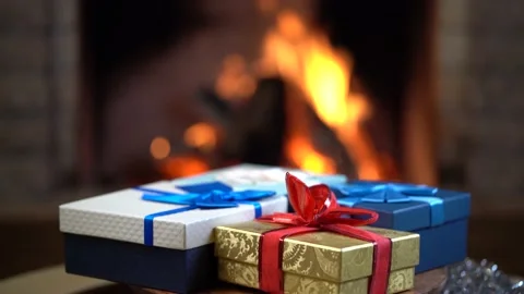 Christmas eve. Gift boxes slowly rotate in front of burning fireplace . Stock Footage 167525684