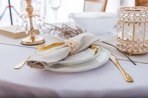 Christmas festive table setting with white plates and gold cutlery, white linen Stock Photos