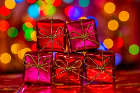 Christmas five red gift boxes on a background of colorful bokeh garland lights Stock Photos