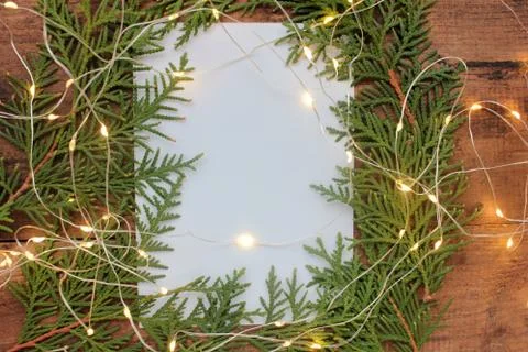 Christmas frame with branches, blank note white shit of paper, and garland Stock Photos