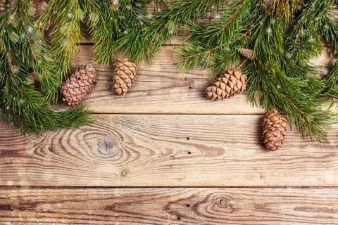 Christmas frame made of pine branches and cedar cones on rustic wooden board. Stock Photos