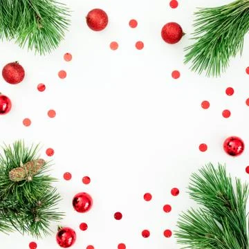 Christmas frame made of pine branches and red balls with confetti on white. F Foto stock