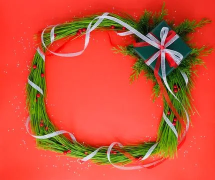 Christmas frame with a present and pine trees on the red background. Foto stock