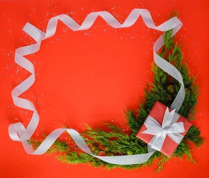 Christmas frame with a present and pine trees on the red background. Foto stock
