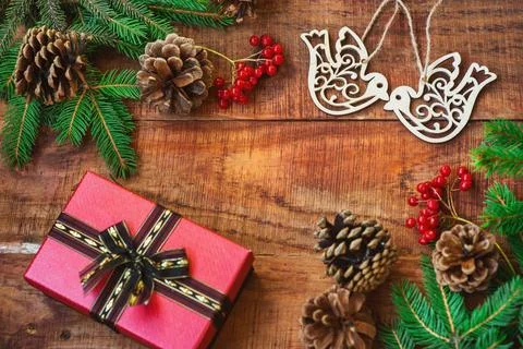 Christmas frame. Spruce branches, red berries, bird figures, gift on a wooden Stock Photos