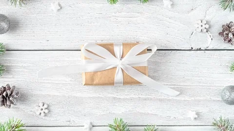 Christmas gift box in frame made of snowy fir branches, decorations, pine cones Stock Footage 293565968