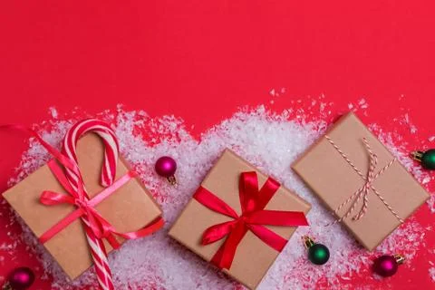 Christmas gift boxes and small balls on red background with decorative snow Stock Photos