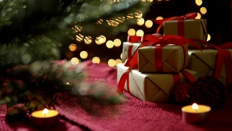 Christmas gift boxes, candle, tree decoration on red scarf with bokeh lights Stock Footage 81409368
