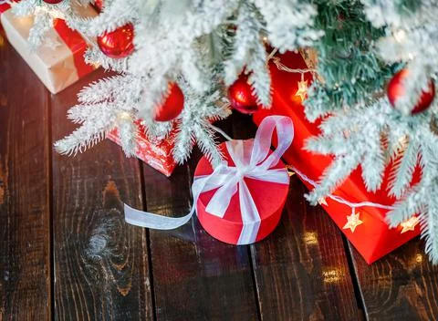 Christmas gift boxes under the tree, on the wooden floor. Stock Photos