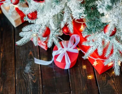 Christmas gift boxes under the tree, on the wooden floor. Stock Photos