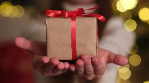 Christmas gift close up. Kid hands holding gift box on background of lights Video stock 219717843