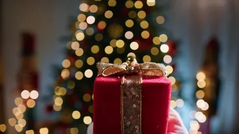 Christmas Gift Held in Hand with Glowing Tree Lights in Background Stockbeeldmateriaal 331106086