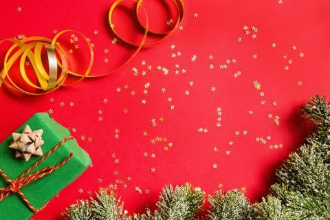 Christmas gift, tree branches on red background with golden confetti. new yea Stock Photos