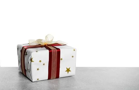 Christmas gift wrapped in star patterned paper on grey table against white .. Stock Photos