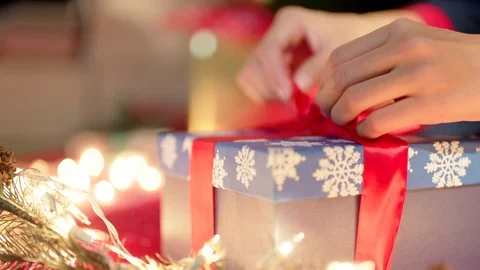 Christmas gift wrapping. Hands tie a gift with a red ribbon on Christmas Eve Stock Footage 74138397