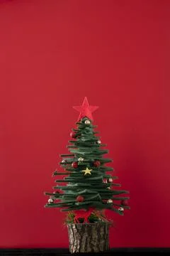 Christmas greeting background with pine tree shaped ornaments over red surfac Stock Photos